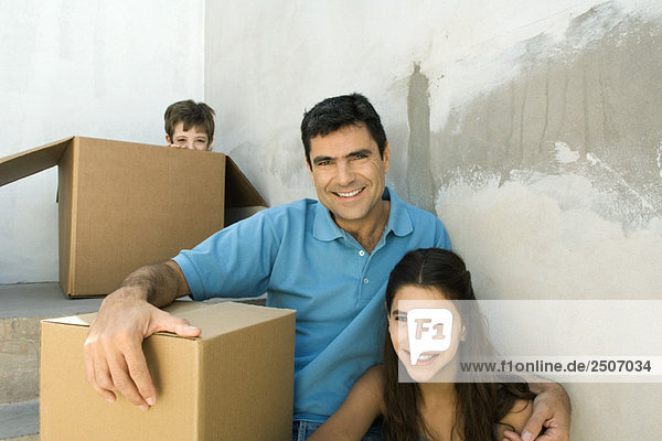Familie sitzend auf dem Treppenhaus mit Pappkartons  Junge versteckend