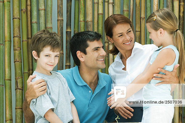 Family smiling at each other in front of bamboo  group portrait  boy looking at camera