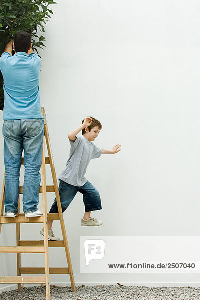 Vater und Sohn auf der Leiter stehend  Junge springt ab