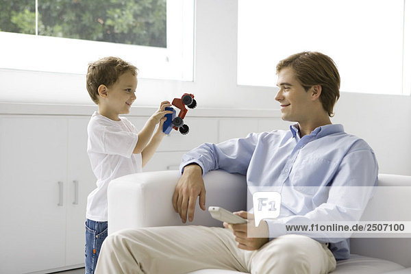 Kleiner Junge zeigt seinem Vater einen Spielzeug-LKW  Mann mit Fernbedienung