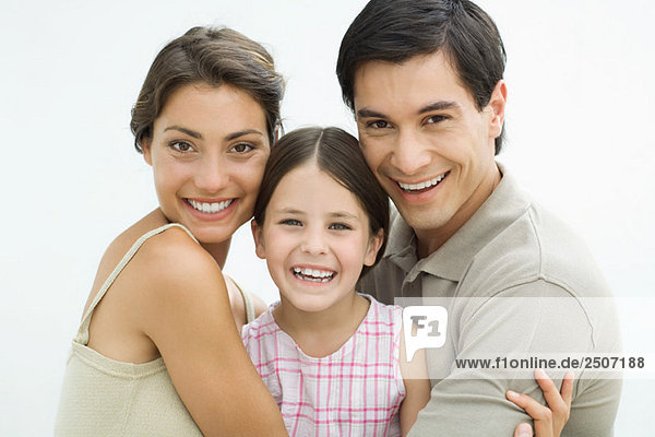 Junge Eltern mit Mädchen dazwischen  lächelnd vor der Kamera  Porträt