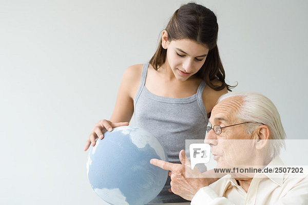 Großvater und Enkelin schauen gemeinsam auf den Globus