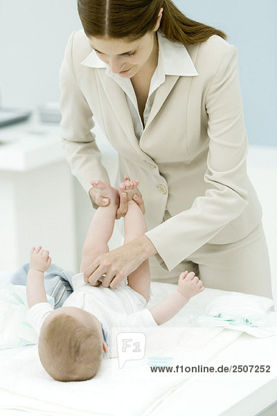 Professionelle Frau beim Wickeln von Babywindeln auf dem Schreibtisch