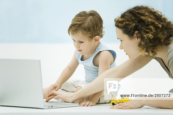 Mutter und Sohn benutzen gemeinsam einen Laptop.