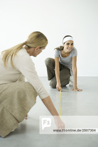 Mother and daughter using measuring tape on the floor