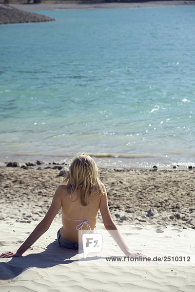 Italien  Blondes Mädchen entspannt am Strand  Rückansicht