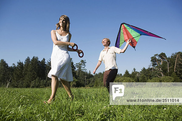 Germany  Bavaria  Young couple flying kites in meadow