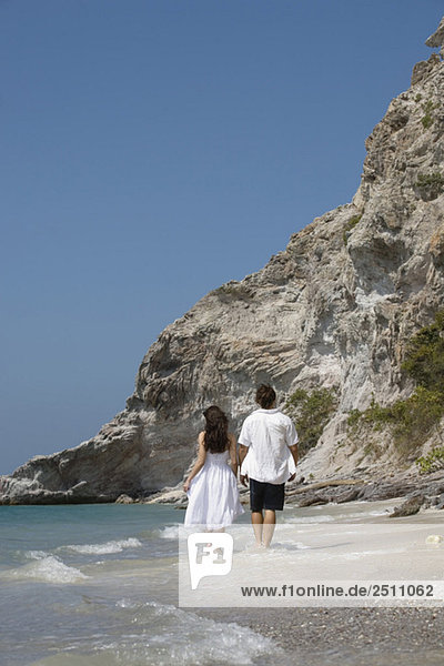 Asien  Thailand  Junges Paar geht Hand in Hand am Strand entlang  Rückansicht