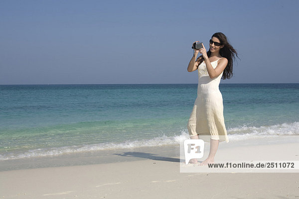 Asia  Thailand  Young woman filming on beach