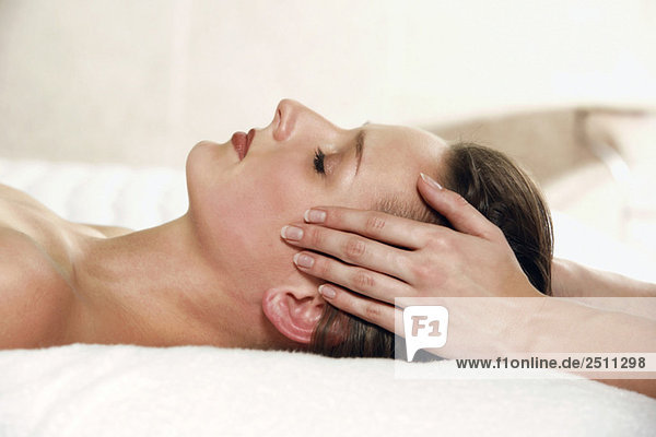 Young woman receiving facial massage  eyes closed