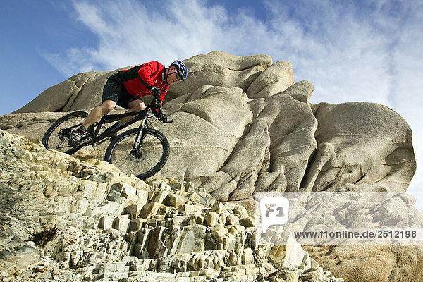 Low angle view of man cycling at coast  Capo Testa  Italy