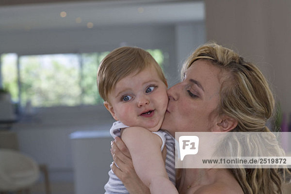 Mother kisses her baby at home