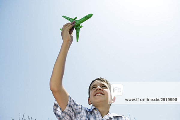 Junge hält Spielzeugflugzeug in der Luft