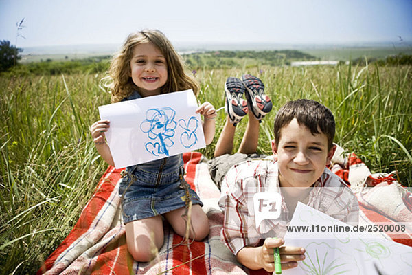 Zwei Kinder zeigen ihre Zeichnungen