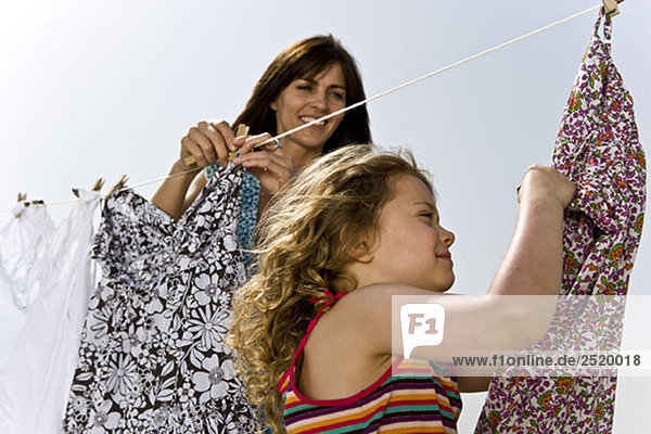 Mädchen hilft Mutter beim Aufhängen von Kleidung