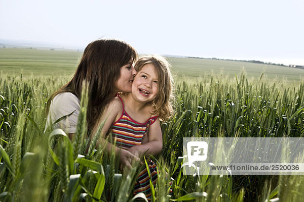 Mutter küssendes Kind im Weizenfeld