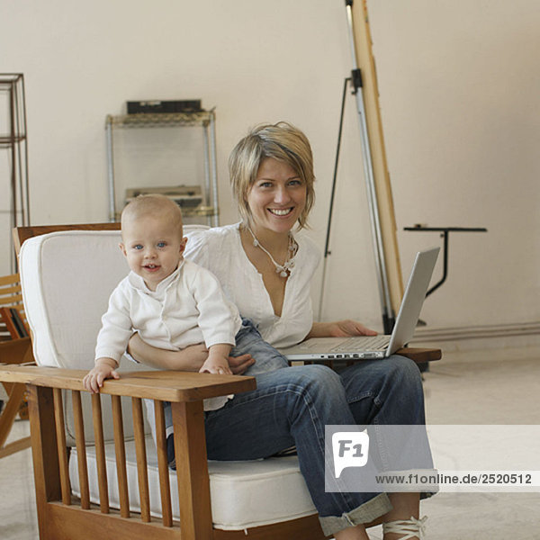 Mother sitting at laptop with young son