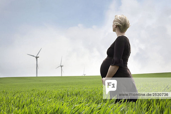 Schwangere Frau schaut auf Windkraftanlagen