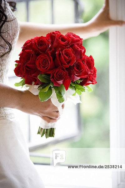 Bride hält Bouquet am Fenster