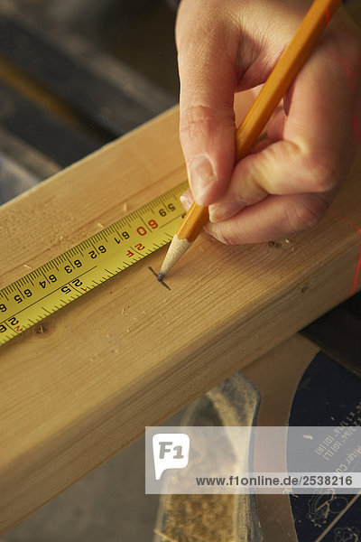 Marking 2 Feet with Measuring Tape on Wood