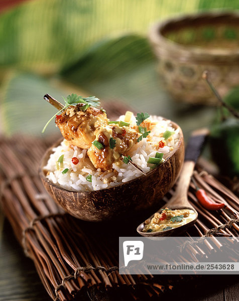 Chicken brochette with coconut milk rice in a coconut shell
