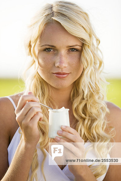 Portrait of young woman eating a yoghurt