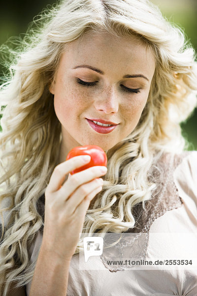 Junge Frau hält eine Tomate in der Hand