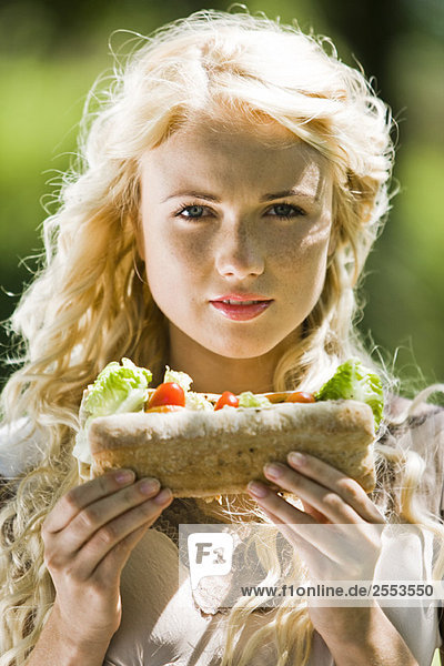 Porträt einer jungen blonden Frau mit einem Sandwich