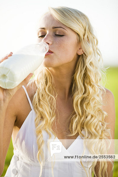 Junge Frau trinkt Milch aus der Flasche