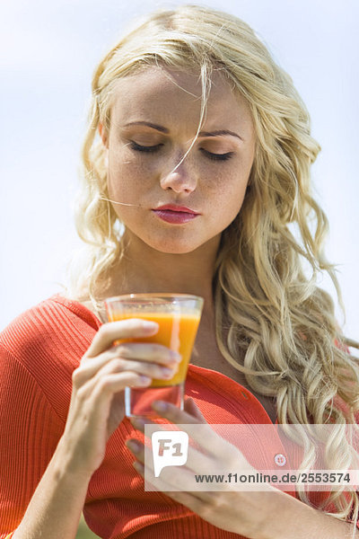 Portrait of a young blond woman holding a fruit juice glass