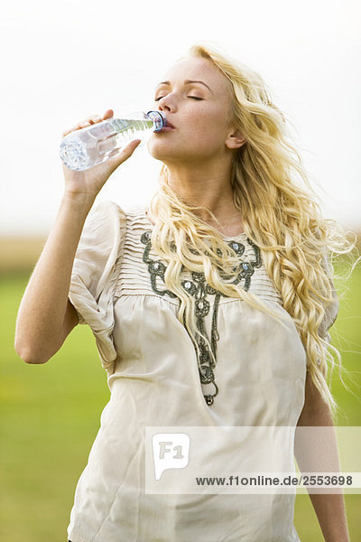 Junge Frau trinkt Wasser aus einer Flasche