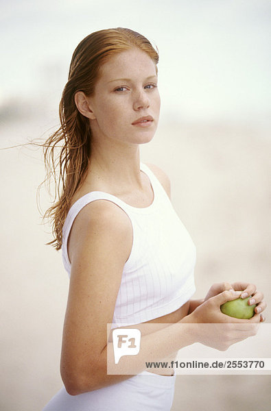 Junge Frau hält einen Apfel  im Freien