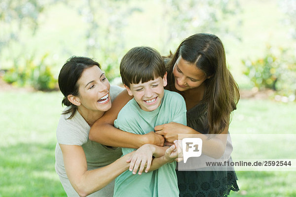 Mother with teenage daughter and son tickling each other