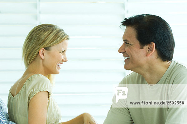Ein Paar sitzt zusammen  schaut sich an  lächelt.