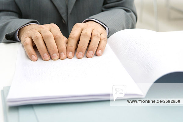 Mann liest Braille-Dokument am Schreibtisch  Ausschnittansicht