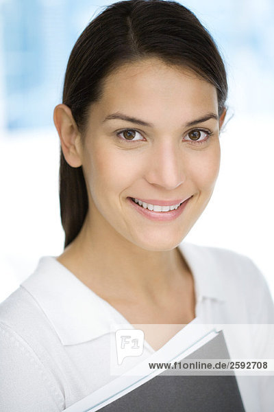 Young woman holding folder  smiling  portrait