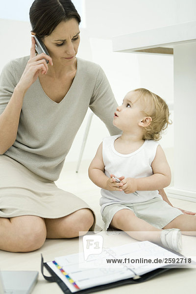 Frau sitzend mit Kleinkind  mit Handy und Blick auf die Tagesordnung