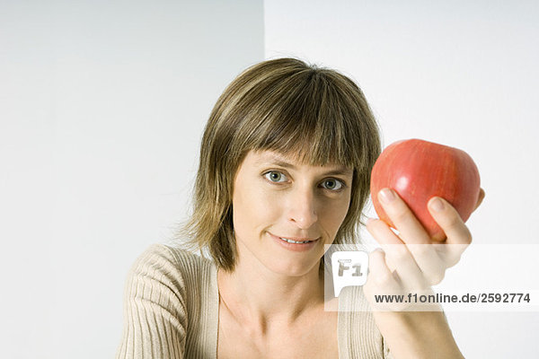 Frau mit rotem Apfel  lächelnd vor der Kamera