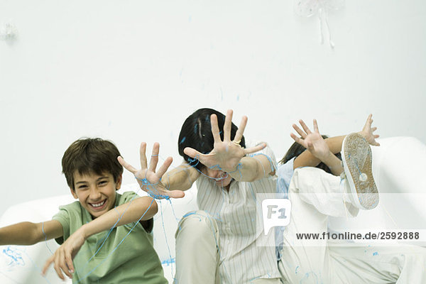 Mutter und zwei Söhne werden mit Schnur besprüht  lachend  die Hände erhoben