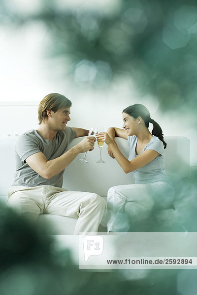 Paar sitzt zusammen auf dem Sofa  Toast mit Champagner