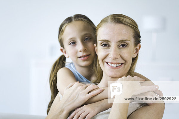 Mother and daughter embracing  both smiling at camera