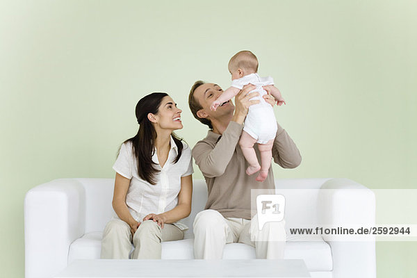 Parents sitting together on sofa  man holding baby