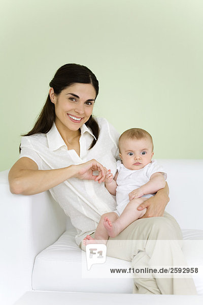 Woman holding baby on her lap  smiling at camera