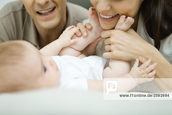 Eltern lächeln das Baby an  Mutter hält die Füße des Babys  Ausschnittansicht
