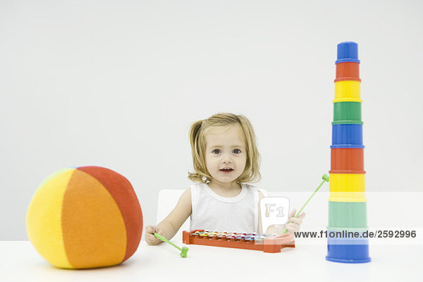 Kleinkind Mädchen sitzend mit Spielzeug  Xylophon spielend  lächelnd vor der Kamera