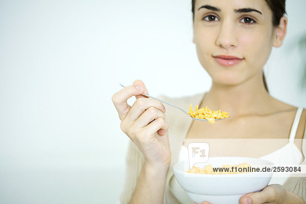 Young woman holding bowl of cereal  smiling at camera