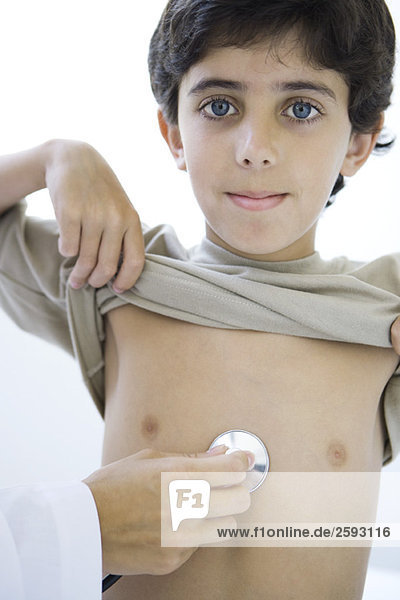 Arzt platziert Stethoskop auf der Brust des Jungen  Junge lächelt in die Kamera  abgeschnitten