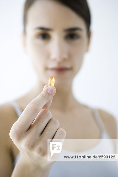 Woman holding vitamin capsule  focus on foreground