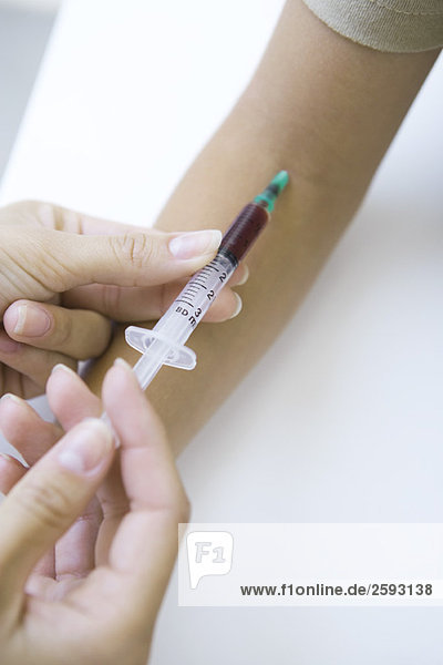 Arzt nimmt Patientenblut mit Spritze  Schnittansicht