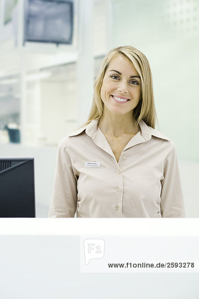 Businesswoman standing behind counter  smiling at camera  portrait